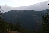 Sokol od severozápadu. Pohled z podobné nadmořské výšky dává vyniknout plochému temeni hory s výraznými skalisky na jihozápadním okraji.