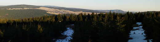 Panoramatický pohled z posedu na Zaječí hoře. V levé části dominuje Blatenský vrch, za nímž mírně vykukuje německý Fichtelberg. Následují méně patrný Božídarský Špičák, Klínovec s vysílačem, nad kostelem zalesněná Smrčina a vpravo Plešivec.