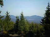 Pohled z vrcholu tisícovky V pařezí na severovýchod. Vlevo mezi stromky Boubín, uprostřed nevýrazný vrchol tisícovky Solovec a vpravo výrazný vrchol Bobíku.