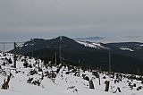 Pohled z vrcholu Svarohu na Malý Ostrý a Ostrý, před nimi oblý vrchol Velkého Kokrháče. Na lysém hřebínku je patrná skalka Ostrého - S vrcholu a v dálce vzadu je Skalka a Čerchov v Českém lese.