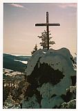 Vrcholová skalka s křížem na Špičáku s pozadím rakouských Alp Totes Gebirge s Gr. Prielem (2523 m).