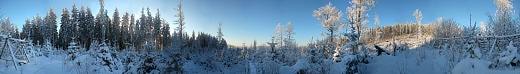 Kruhové panorama z paseky jižně od vrcholu Stožce. Podvečerním sluncem ozářený vrchol dominuje v pravé části snímku.