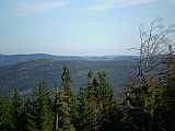 Pohled z vrcholové skály tisícovky V pařezí na východ. Uprostřed částečně viditelná "kouřící" Jaderná elektrárna Temelín.
