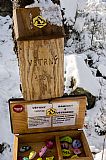 Vrchol Větrný je velice pěkně výtvarně doplněn. Kromě lavice na vrcholové skále je zde dřevěná schránka s vrcholovou knihou a schránka s malovanými kamínky.