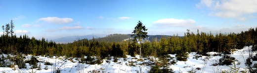 Panoramatický snímek z vrcholu Doupné hory - SV vrchol II přes Větrný, v pozadí v oparu vlevo Boubínský hřbet se zleva Jedlovou, Zátoňskou horou, Zátoňskou horou - SV vrcholem a Bobíkem. Vpravo za stromy Libínský hřbet: Libín, Na skalce a Rohanovský vrch.